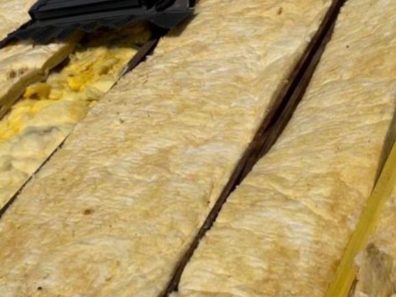 Combles aménagés : isolant posé entre chevrons autour d'une fenêtre de toit