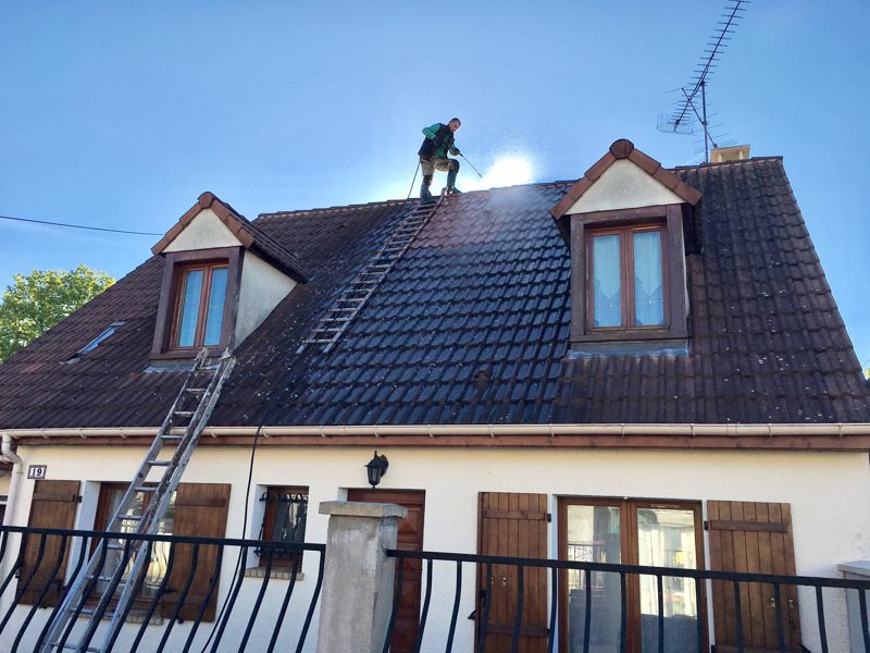 Démoussage de toiture : couvreur intervenant sur le versant