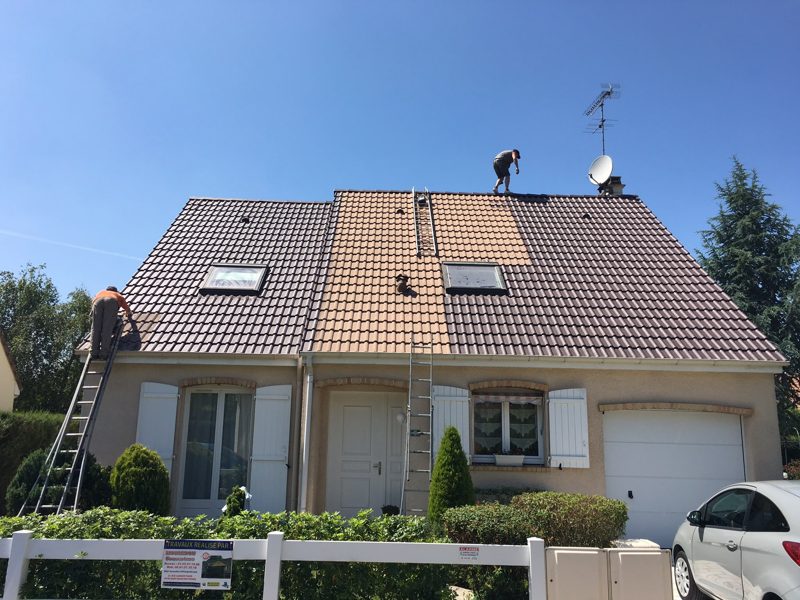 Démoussage de toiture : traitement en cours sur une maison